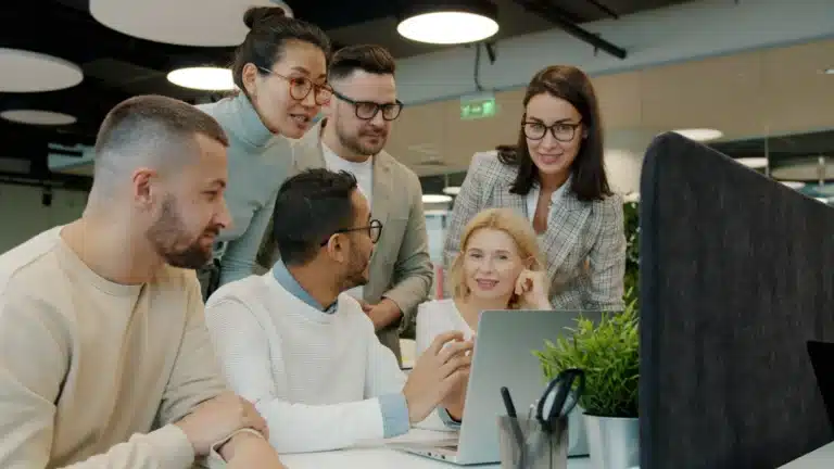 Team arbeitet im Büro gemeinsam an einem Laptop
